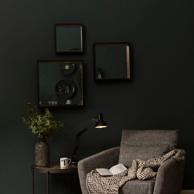 Cozy living room with a gray armchair, coffee table, and decorative items against a dark wall.