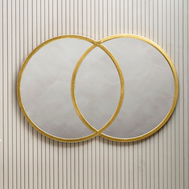 Two round mirrors with gold frames on a wall with vertical stripes.