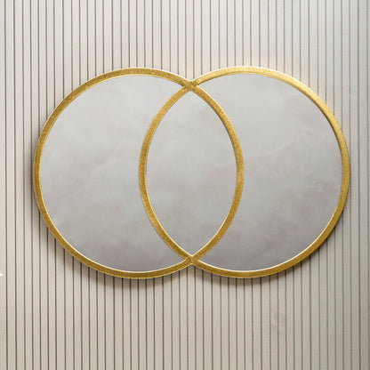 Two round mirrors with gold frames on a wall with vertical stripes.