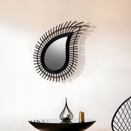 Decorative wall mirror with black wicker-like frame on a white wall.