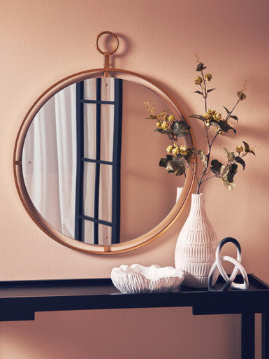 Round mirror with wooden frame on a wall above a dark surface with decorative items.