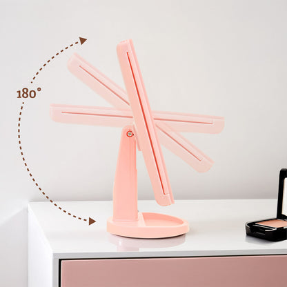 Pink adjustable desk lamp on a white surface with a neutral background