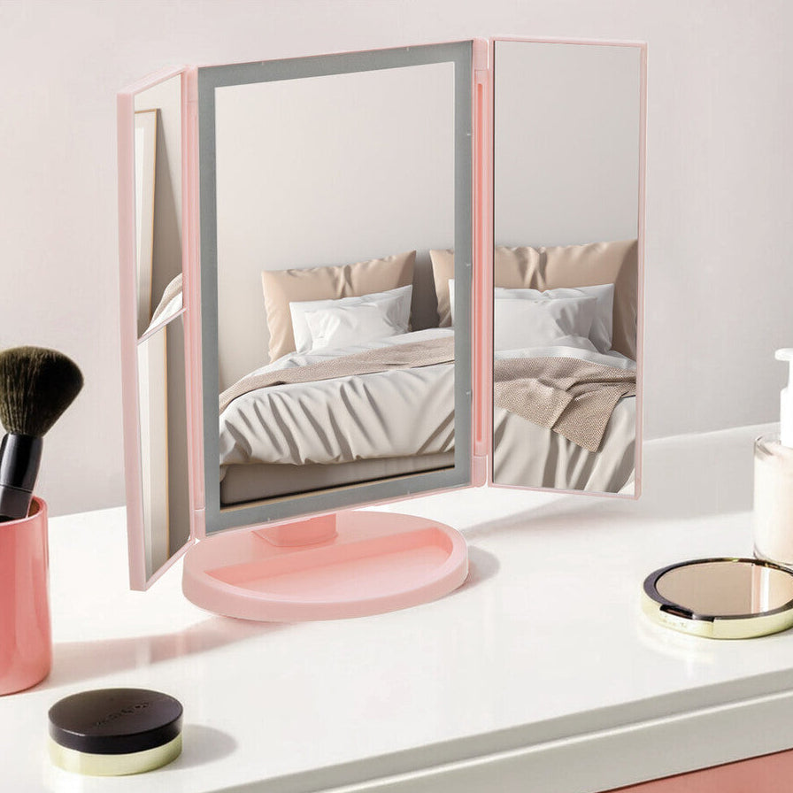 Pink vanity mirror on a desk with makeup items and text &