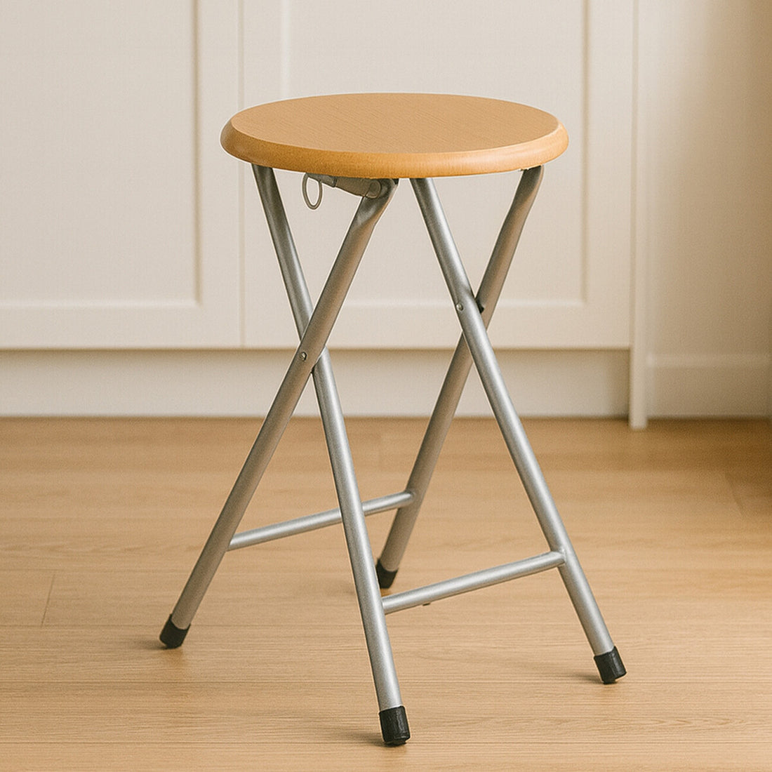 Foldable stool with wooden seat and metal frame on a wooden floor.