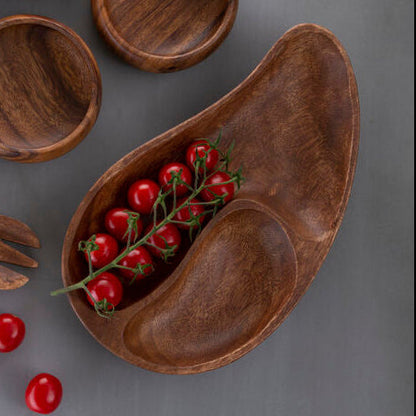 Wooden utensils and bowls with red berries on a gray background