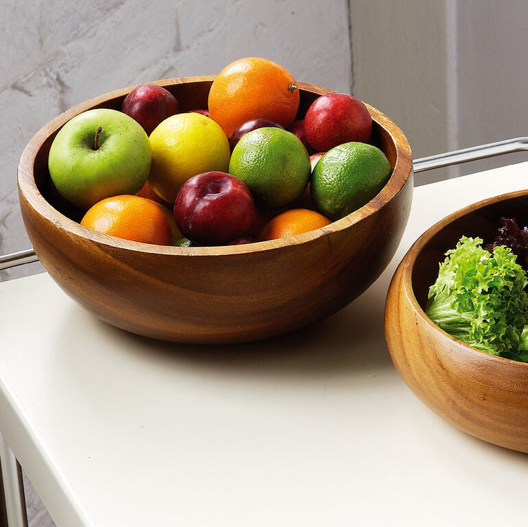 Two wooden salad bowls with fruits and vegetables on a white surface.