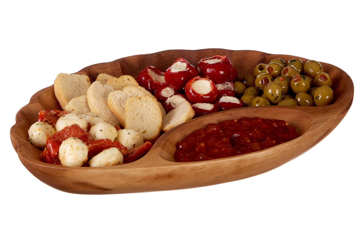 Wooden platter with assorted snacks including olives, cheese balls, and crackers on a white background