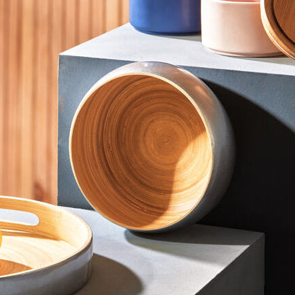 Wooden bowls and ceramic plates on a modern surface with a wooden wall background