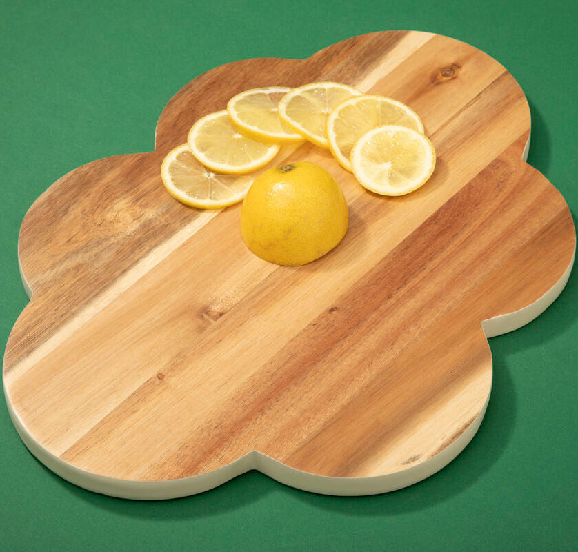 Wooden cutting board with sliced lemons on a green background