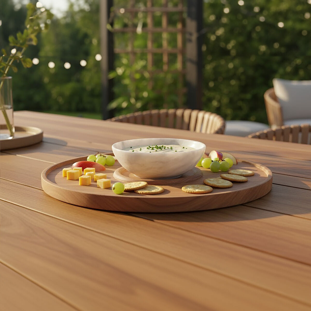 Outdoor setting with a wooden table, bowl of salad, and snacks on a tray.