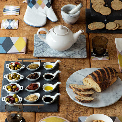 Table setting with teapot, bread, and various condiments on a wooden surface.