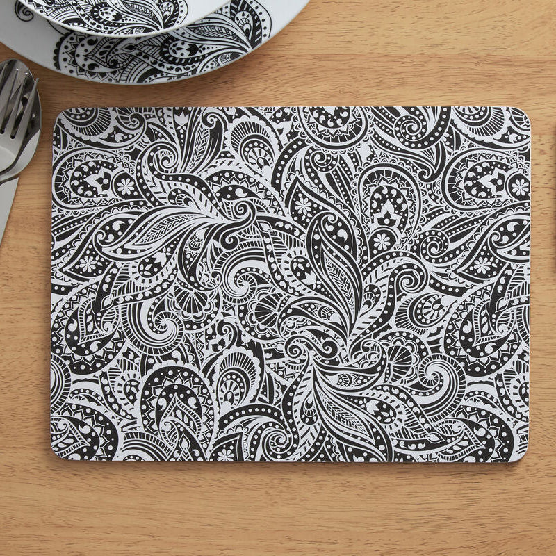Black and white paisley patterned placemat and coaster on a wooden table.