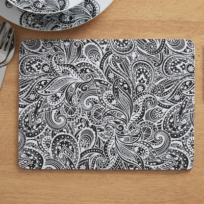 Black and white paisley patterned placemat and coaster on a wooden table.