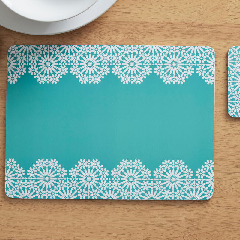 Teal placemat with white lace pattern on a wooden table