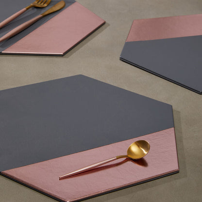 Hexagonal placemats with pink and gray design on a table setting.