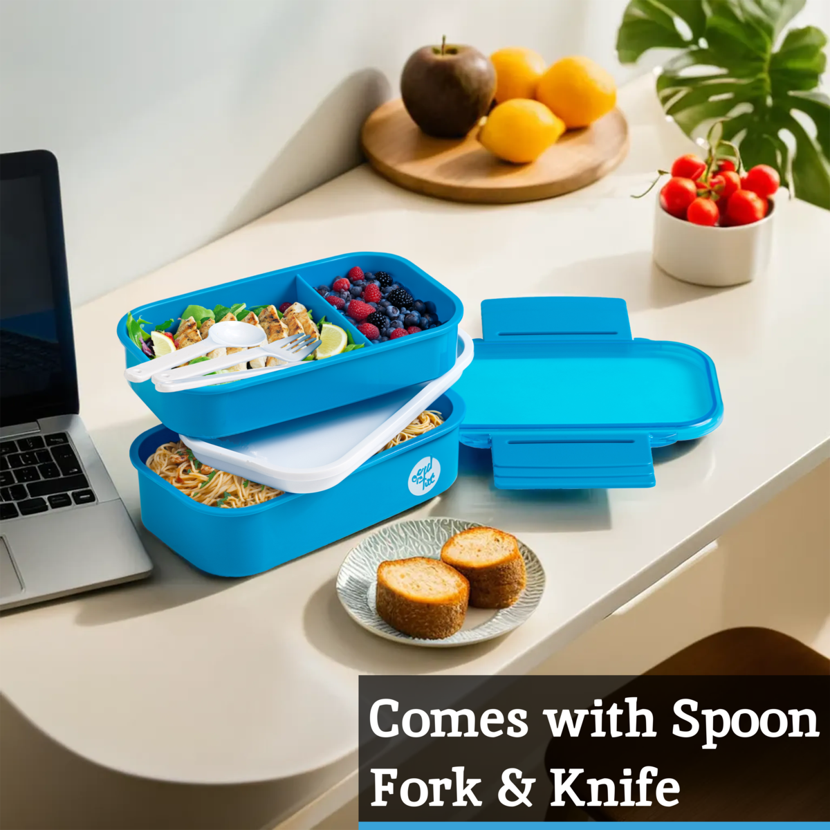 Blue bento box with food compartments on a desk with laptop and fruits