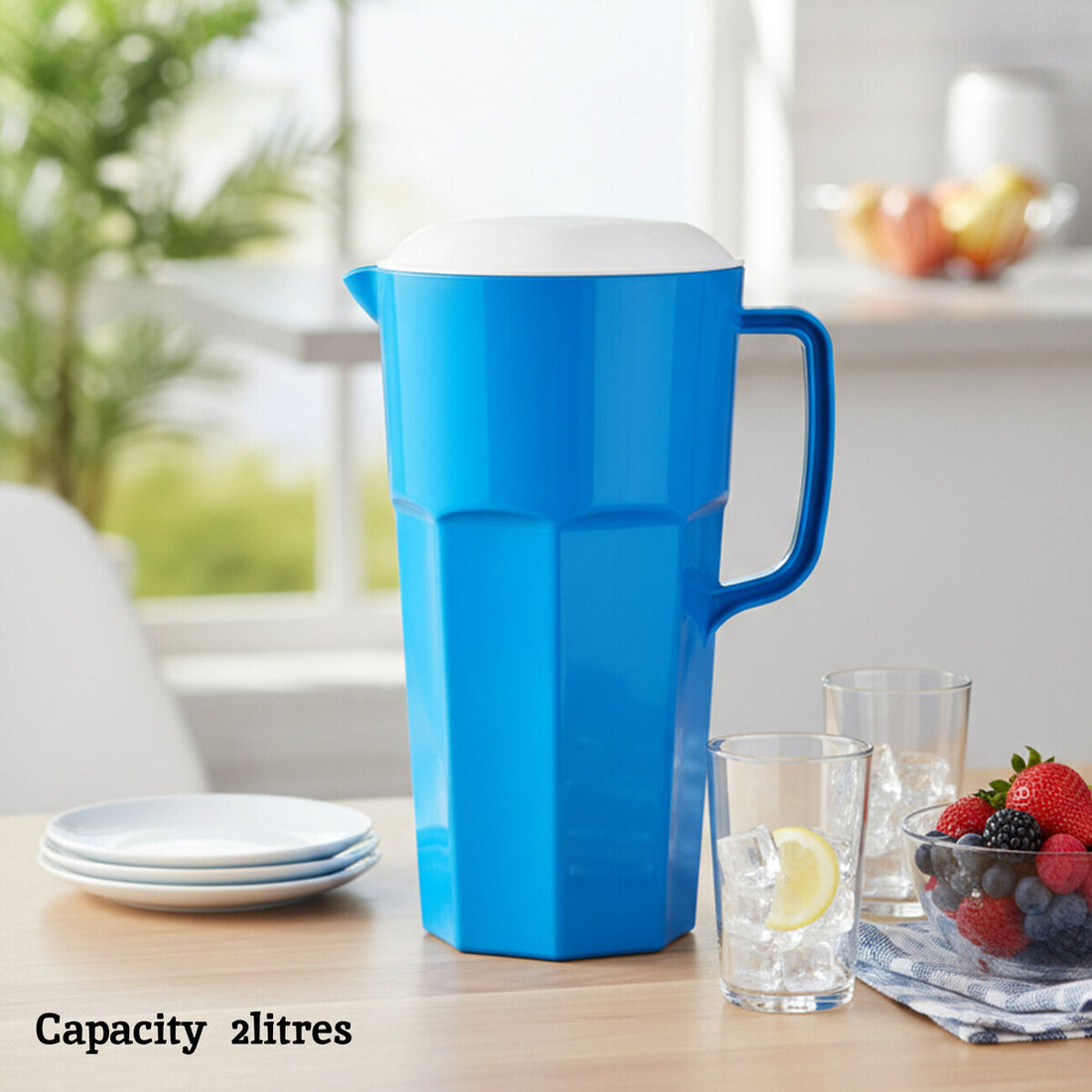 Blue pitcher on a table with glasses and fruit in a kitchen setting