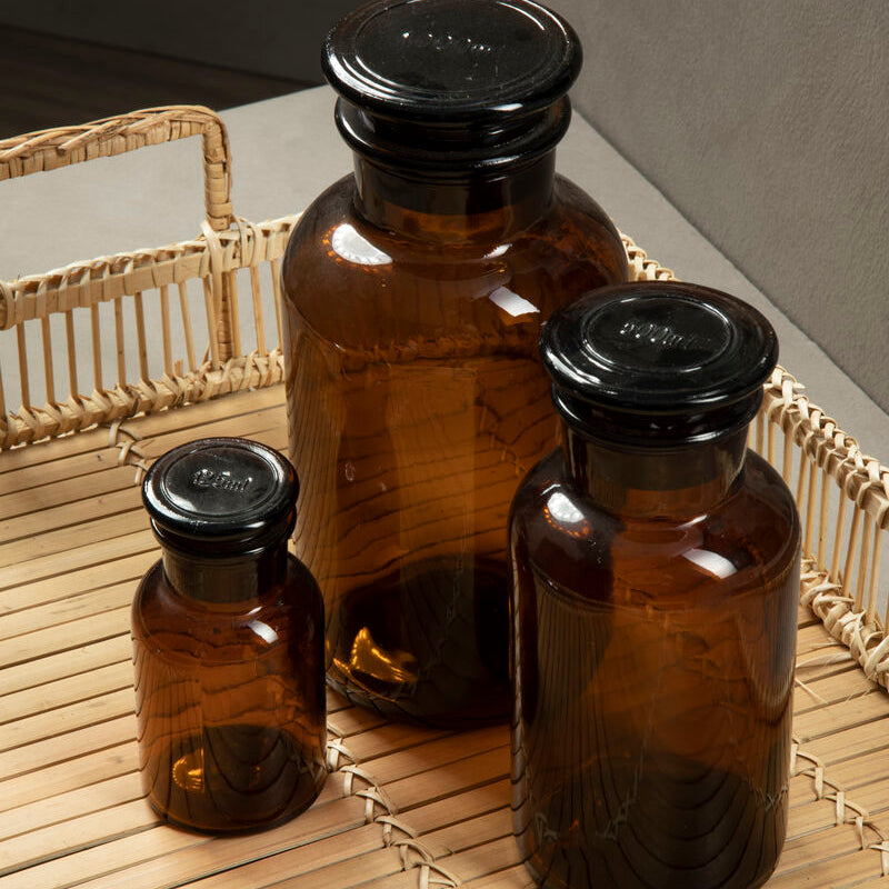 Three brown glass bottles with black lids on a woven surface.