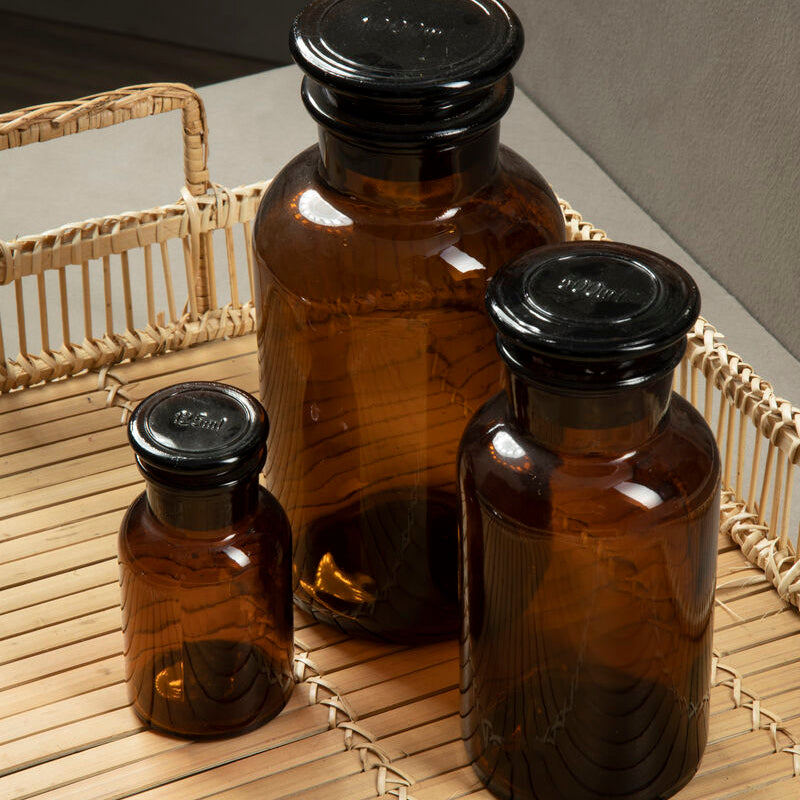 Three brown glass bottles with black lids on a woven surface.