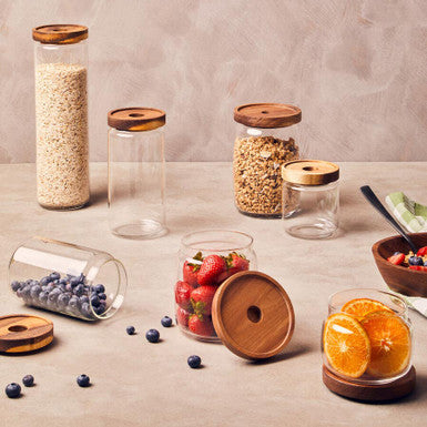 Set of glass jars with wooden lids on a neutral background