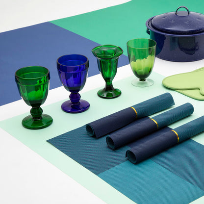 Set of blue and green glassware and cookware on a checkered surface