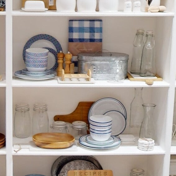 White shelving unit with various kitchen items including plates, bowls, and jars.