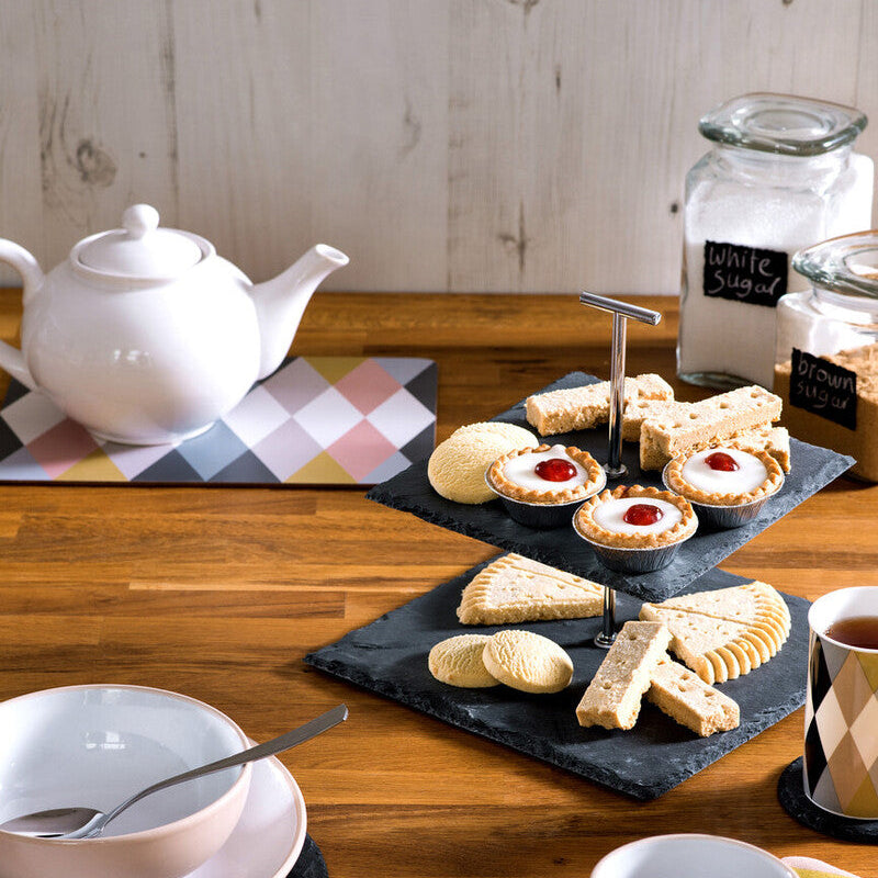 Tea set with a teapot, cups, cookies, and a teacup on a wooden table.