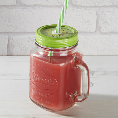 Red juice in a Mason jar with a green lid and straw against a white brick wall.