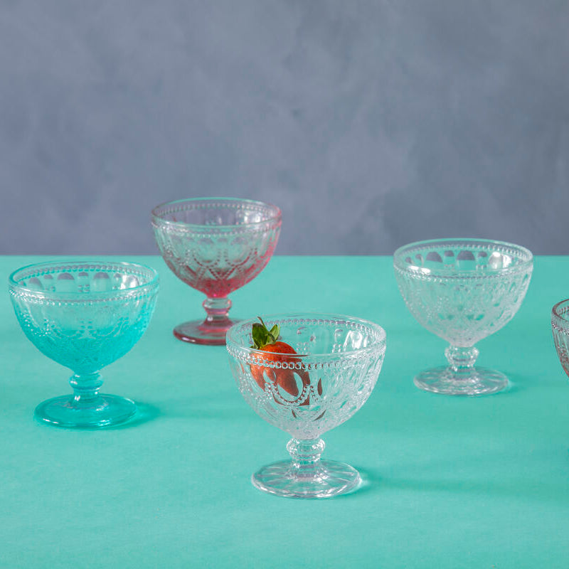 Set of vintage glass dessert bowls on a teal surface with a gray background
