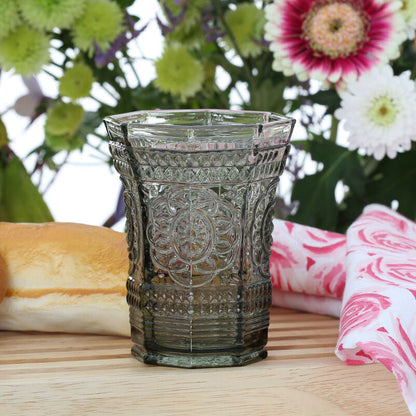 Decorative glass on a wooden table with bread and flowers in the background