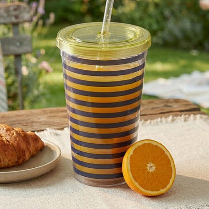 Striped design tumbler with lid and straw on a picnic setting outdoors