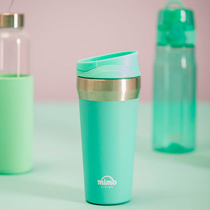 Green travel mug with a silver lid on a light green surface