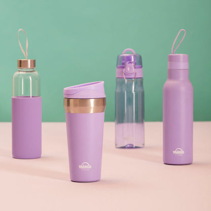 Set of purple water bottles with gold accents on a beige surface against a green background