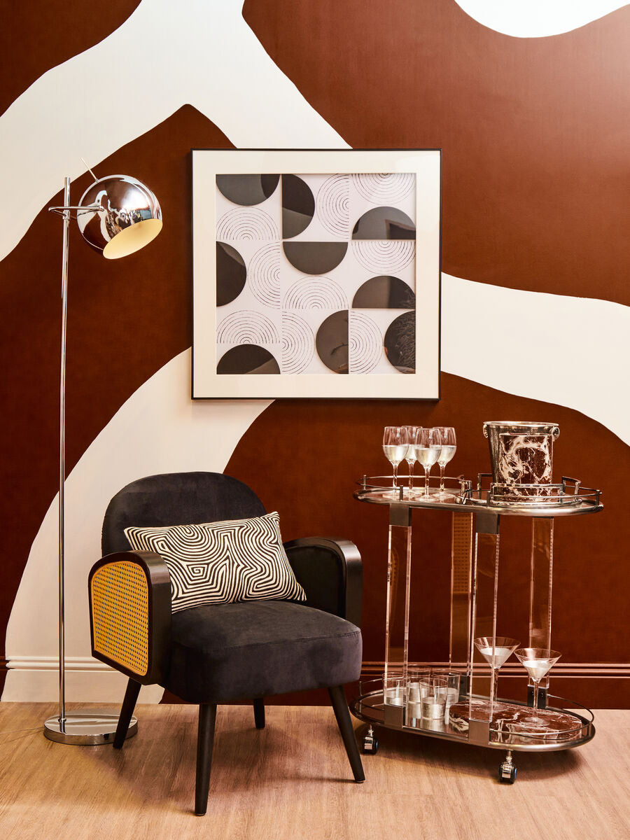 Modern interior with a black armchair, decorative pillows, a floor lamp, and a wall art piece.