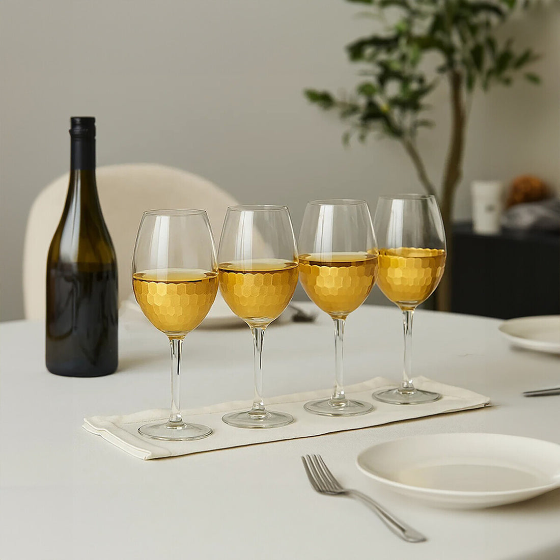 Wine bottle and four wine glasses with white wine on a table.