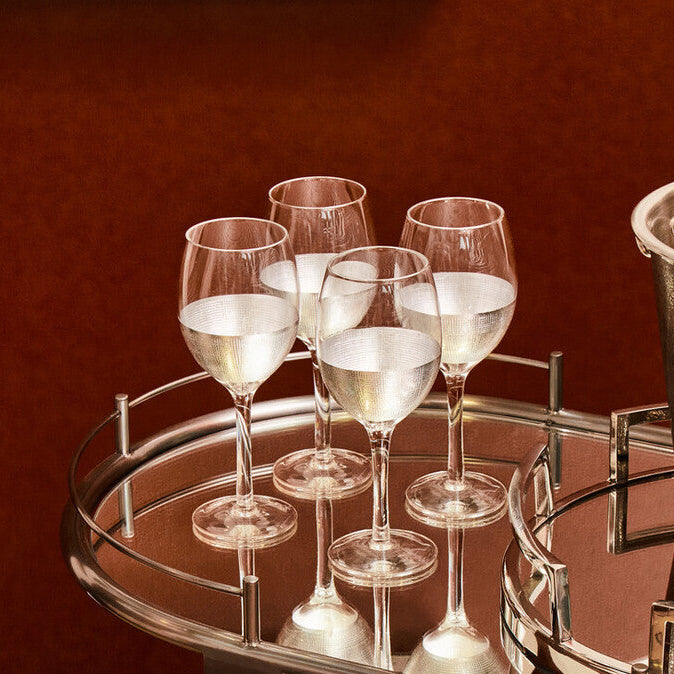 Silver bar cart with wine glasses on a dark red background