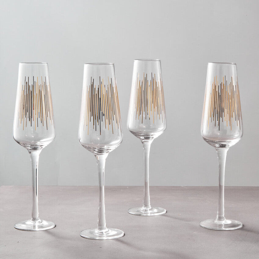Four clear wine glasses with gold accents on a gray surface and light gray background