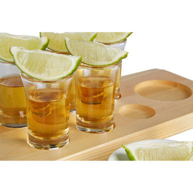 Tequila shots with lime wedges on a wooden tray