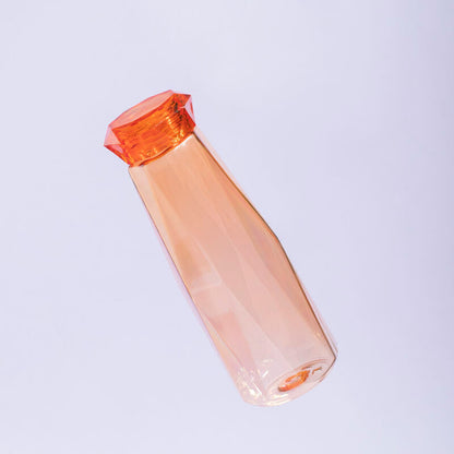 Clear plastic bottle with orange cap on a light purple background