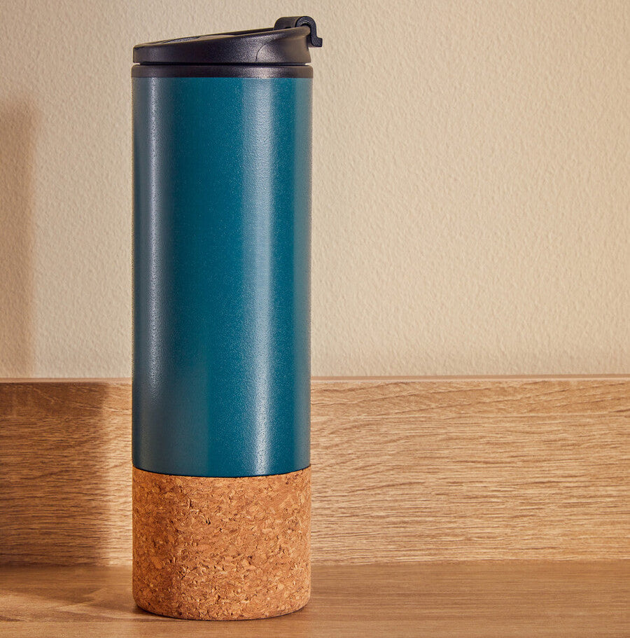 Blue travel mug with cork base on a wooden surface