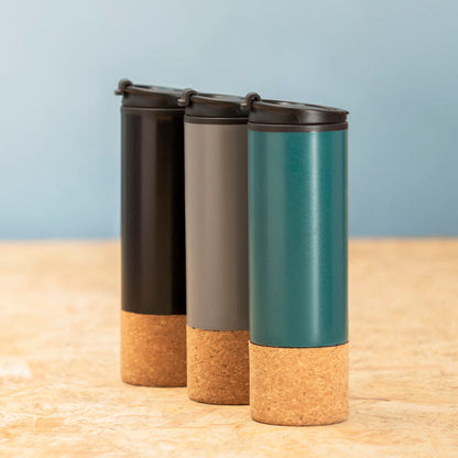 Three cylindrical containers with cork bases on a wooden surface and light blue background