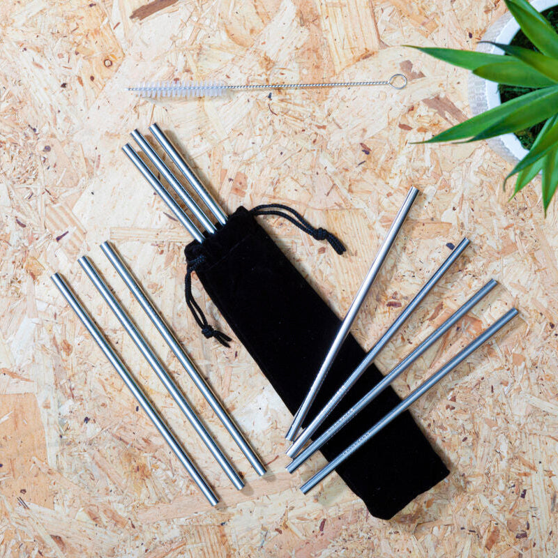 Set of metal straws with a black drawstring bag on a wooden surface.