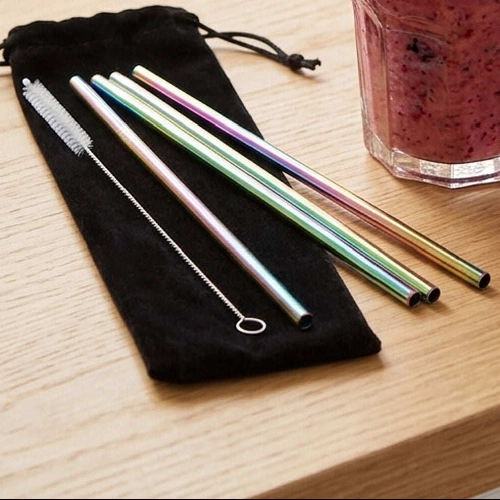 Set of stainless steel straws with a cleaning brush on a black drawstring bag, next to a glass of a berry smoothie.