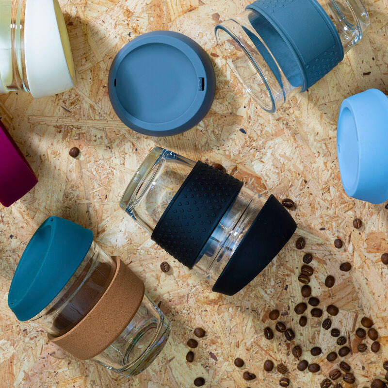 Collection of glass jars with various colored lids on a wooden surface with coffee beans.