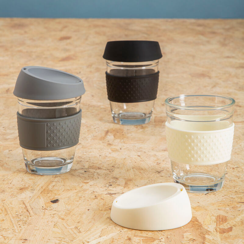 Set of glass cups with various colored lids on a wooden surface