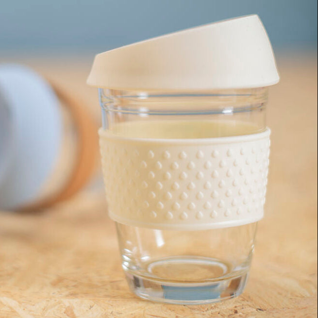 Clear glass with a textured white sleeve on a wooden surface with a blurred gray background
