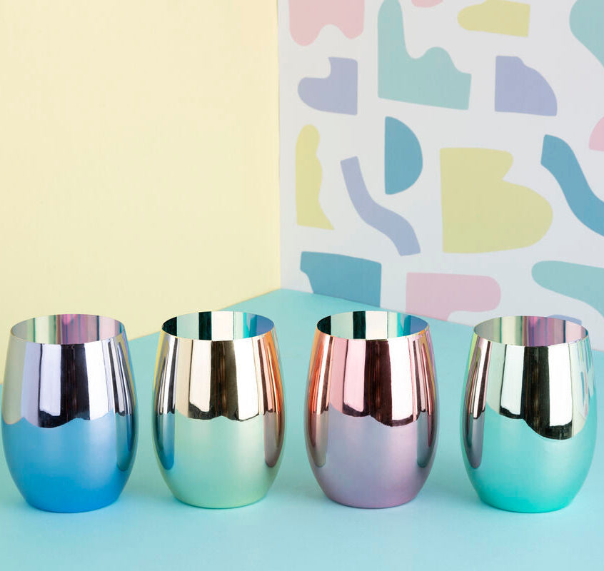 Four iridescent chrome cups on a light blue surface with a colorful abstract pattern in the background.