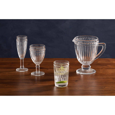 Set of clear glassware including a pitcher and four glasses on a wooden surface with a dark background.