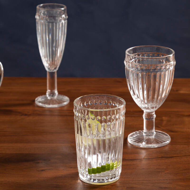 Set of glassware including a tall flute, a short tumbler, and a wine glass on a wooden surface with a dark background.