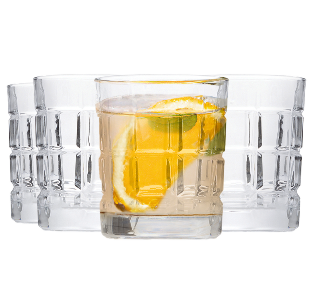 Set of four clear glasses with a drink containing lemon slices on a white background